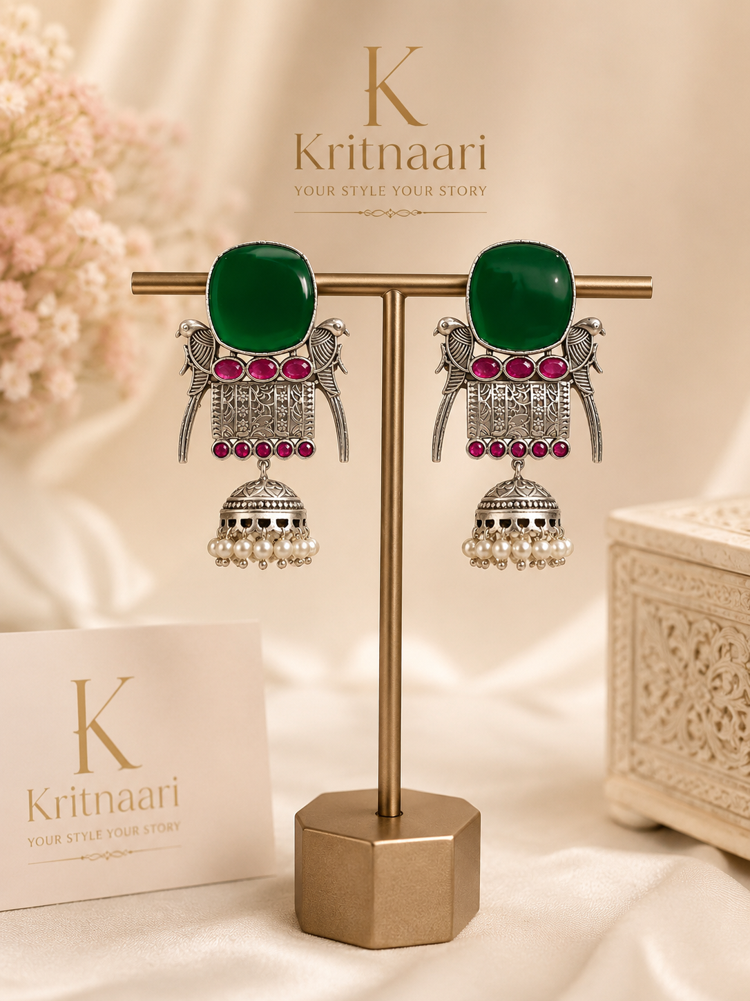Emerald green stone jhumka earrings on display stand - front view