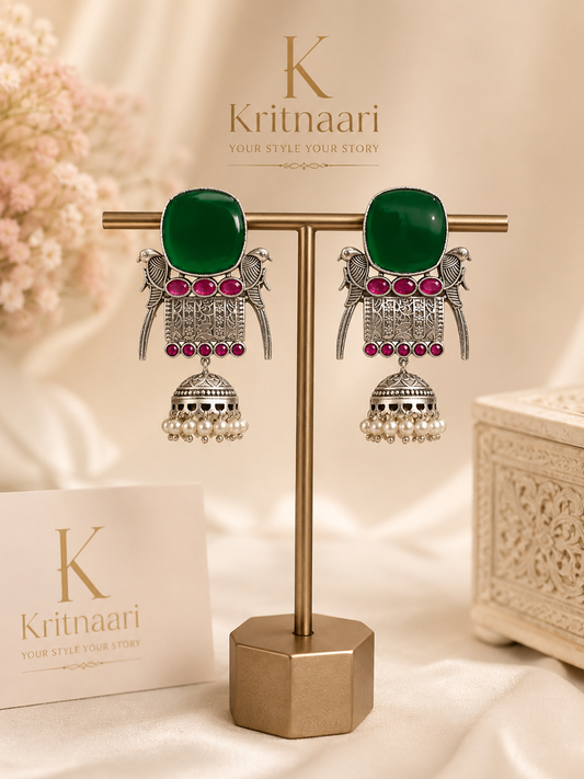 Emerald green stone jhumka earrings on display stand - front view