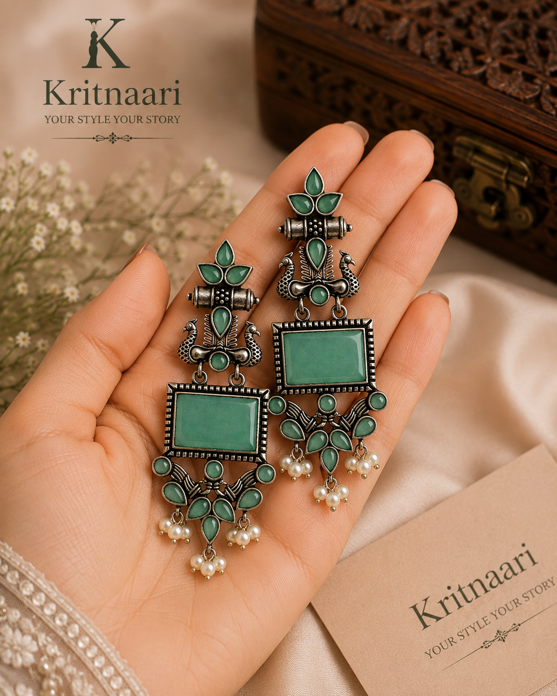 Oxidised silver peacock rectangular stone earrings in emerald green on display cushion